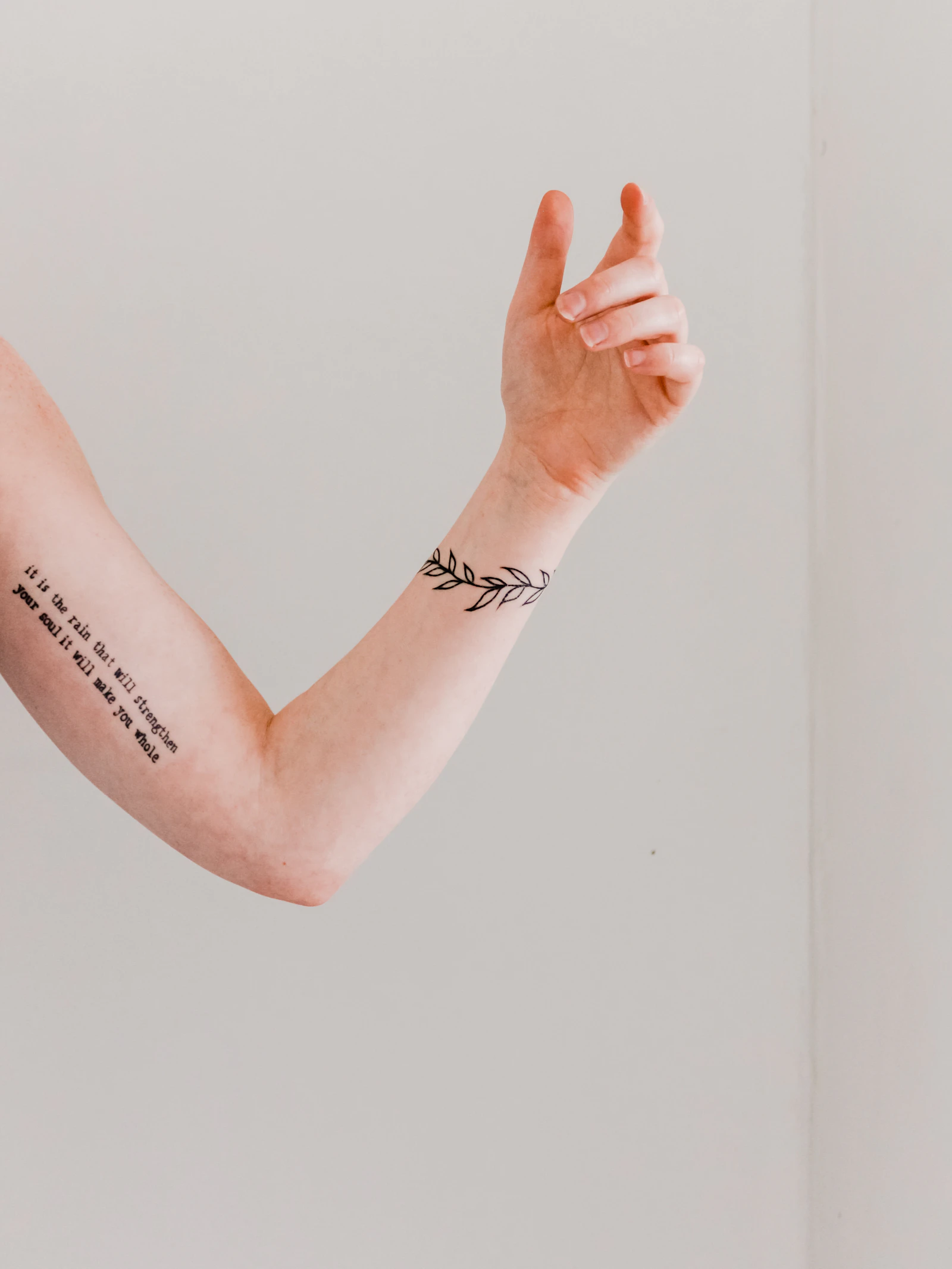 Tattooed forearms against a neutral background